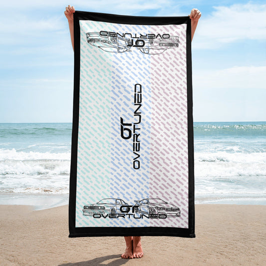 vibrant look towel with car design and black border held on the beach with ocean background